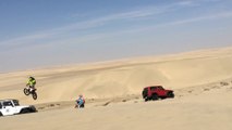 Une motocross fait un saut de 30m dans les dunes et atterrit sur une Jeep