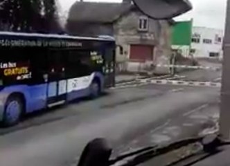 Des voitures et un bus franchissent un passage à niveau fermé