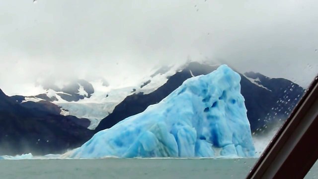 Retournement d'un énorme Iceberg dans l'eau devant un bateau de touristes