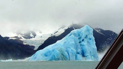Retournement d'un énorme Iceberg dans l'eau devant un bateau de touristes