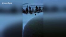 Man clears snow off driveway during blizzard, wearing vest, shorts and flip-flops