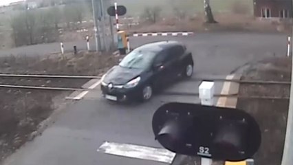 Cette voiture traverse un passage à niveau avec les barrières baissées..
