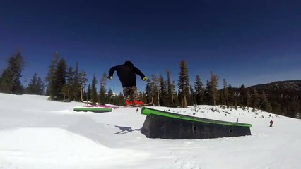 Un skieur pousse un enfant qui passe devant lui sur un tremplin
