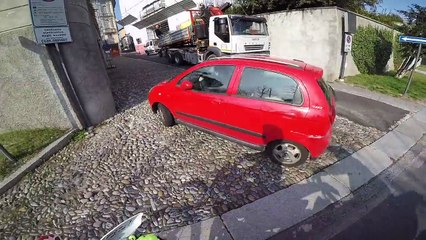 Une femme double sur une ligne continue et frôle le frontal avec un motard.