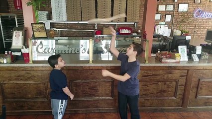 Deux enfants font tourner de la pâte pizza