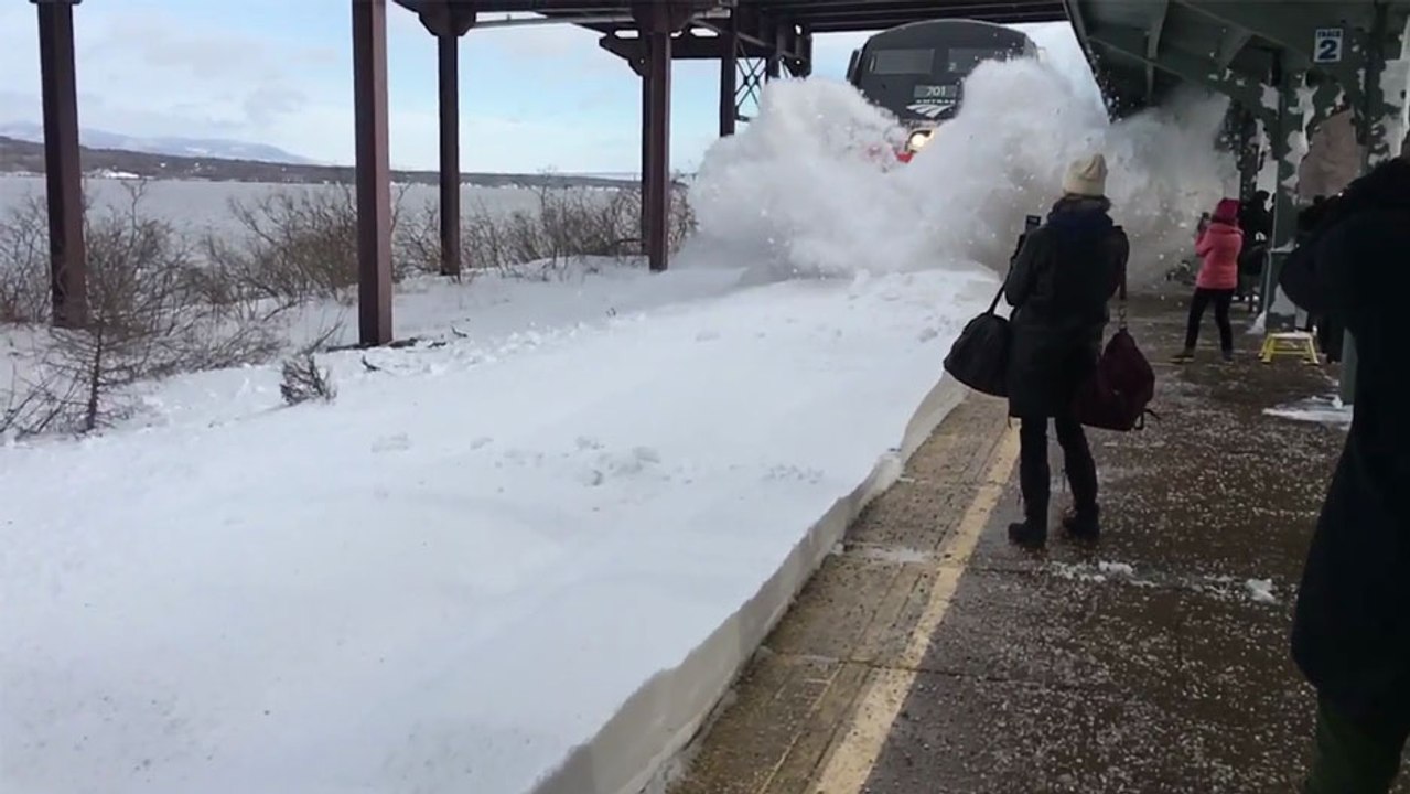 Un train chasse-neige entre dans une gare