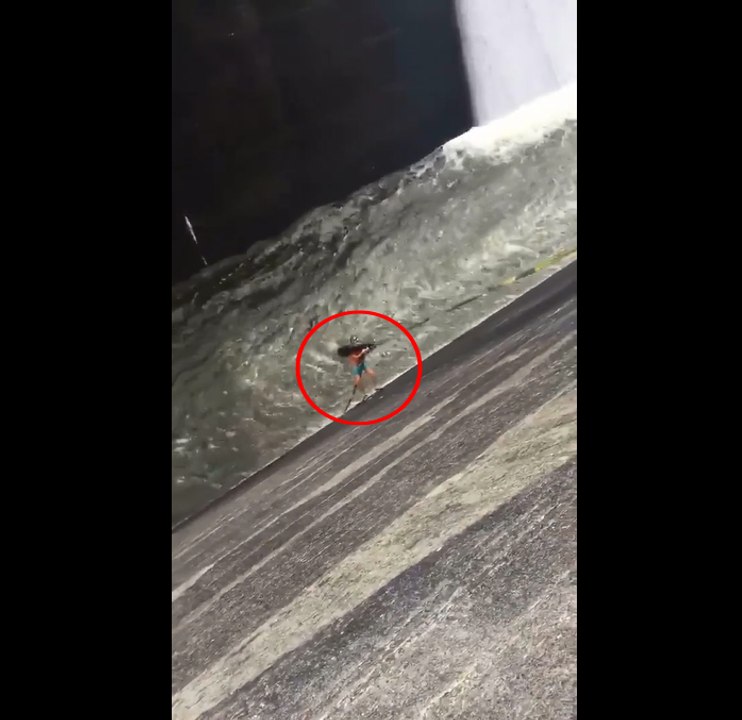 Un homme fait de la bouée sur le déversoir d'un grand barrage.