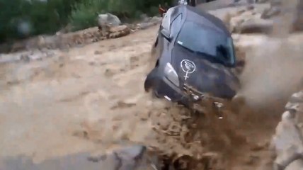 Un homme tente de traverser une route inondé.