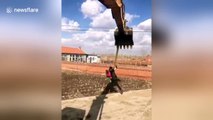 Construction worker dances with dummy while hanging on excavator