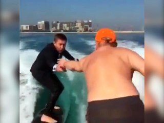 Un homme boit une coupe champagne sur une planche de surf !