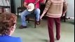 A man playing the banjo. Shortly after the 85 year old woman takes off his shoes and start dancing