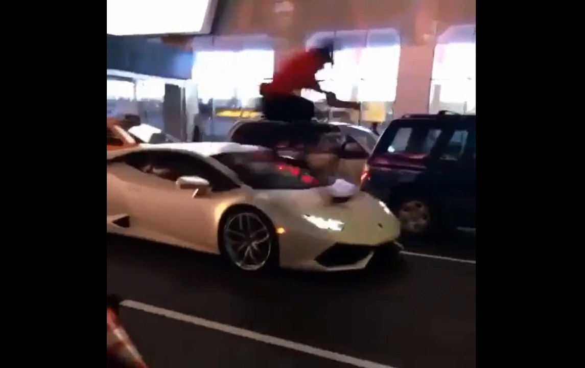 Il roule sur le capot d'une Lamborghini avec son vélo.