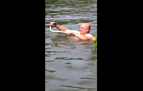Cet homme tente d'attraper un serpent à mains nues dans l'eau.