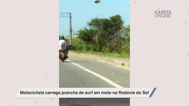 Motociclista carrega prancha de surf em moto na Rodovia do Sol