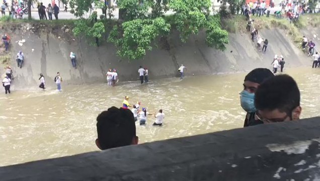 Caracas Demonstrators Scramble to Cross Pipes Over Guaire River as Police Fire Tear Gas
