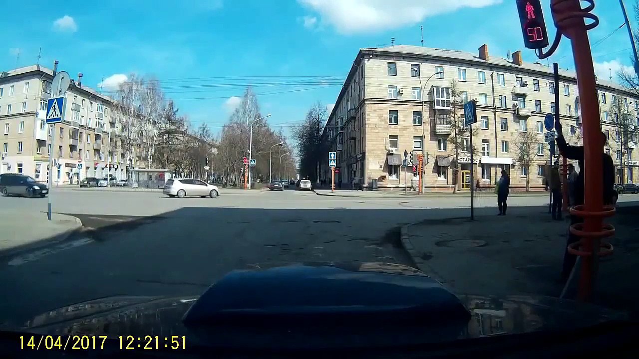 Un piéton pointilleux veut redresser un feu de signalisation mais il fait pire que mieux.