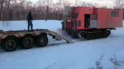 Un russe charge un engin de chantier sur son camion