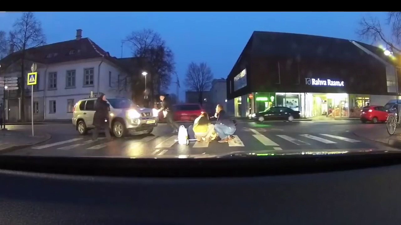Un homme aide une vieille dame à traverser la route mais cela n'est pas au goût de sa voiture !