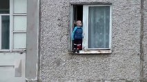 Un enfant joue sur le bord d'une fenêtre au 8ème étage