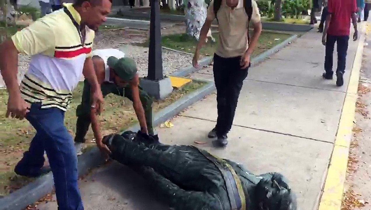 Jóvenes tumban estatua de Hugo Chávez en Venezuela