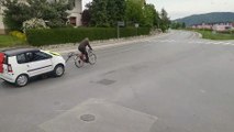 Un homme tracte une voiture avec un transpalette et son vélo