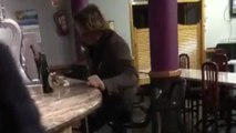 Un homme bourré tente de s'asseoir sur un tabouret..