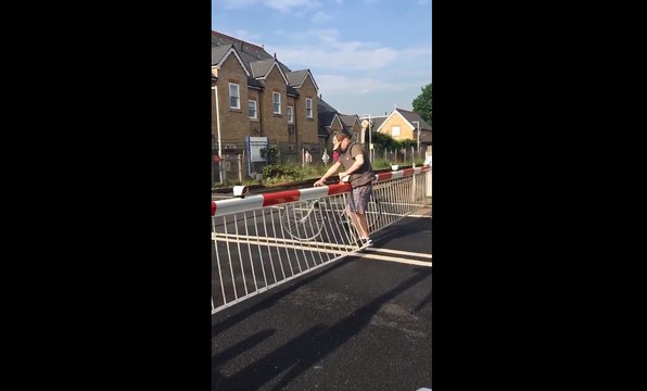 Un cycliste passe les barrières d'un passage à niveau.