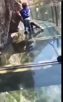Un petit garçon courageux essaie de traîner un père terrifié au cours d'une passerelle en verre en Chine
