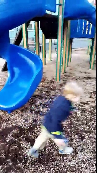 Aden and Ethan trying to knock down the pile of wood chips with their monster trucks at playground