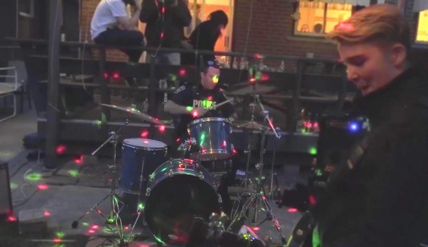 Un policier joue de la batterie avec un groupe de rock