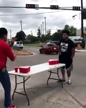 Deux mecs qui jouent au beer pong dans une intersection bloquant la circulation