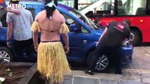 Rugby players dressed in Hawaiian grass skirts physically lift up car