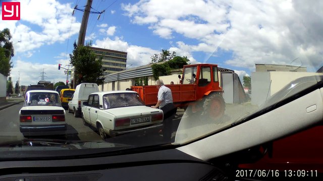 Ce russe essaie de retenir un tracteur sans frein et se retrouve coincé contre une voiture