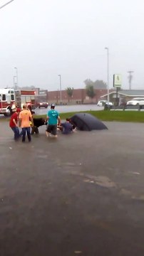 Des hommes interviennent pour sauver une femme piégée dans une inondation avec sa voiture