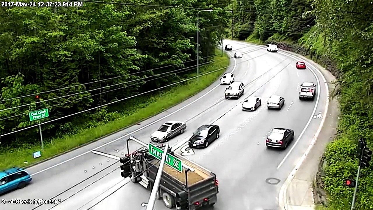 Un camion benne passe à travers un carrefour et emporte une voiture sur son passage.
