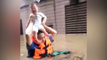 Police officer carries baby over head during deadly Chinese flood