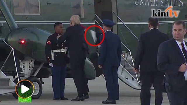 Trump struggles to retrieve marine hat blown off by the wind