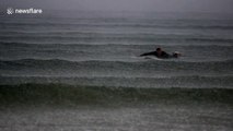 Surfer battles heavy rainfall at Benone beach, Northern Ireland