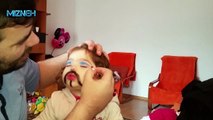 Baby with painted face feeling funny when seeing herself
