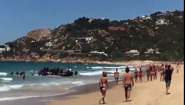 STUNNED TOURISTS WATCH MIGRANTS INVADE BEACH IN SPAIN