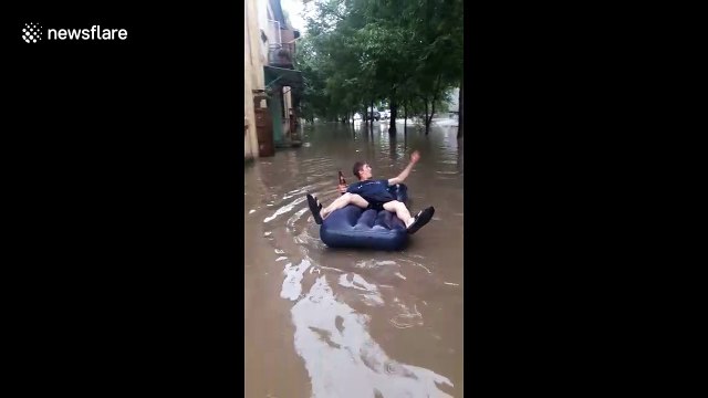 Russian man enjoys floods with lilo and a beer