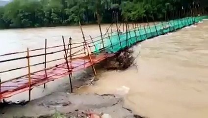 Une femme traverse un pont très fragile vraiment au pire moment