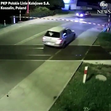 Une voiture passe sur une voie ferrée alors qu'un train arrive