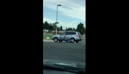 Un homme se fait traîner au sol par une voiture.