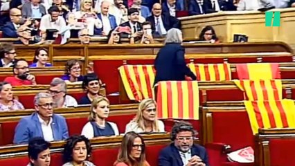 Una diputada retira las banderas de España dejadas por el PP en los escaños del Parlament