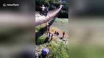 Suspension bridge tips over sending tourists into river