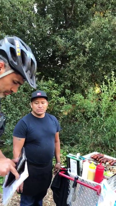 Un policier prend l'argent d'un vendeur de hot dog