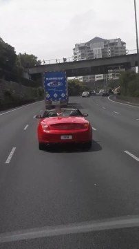 Ces parents inconscients laissent leur enfant debout à l'arrière de leur voiture décapotable..