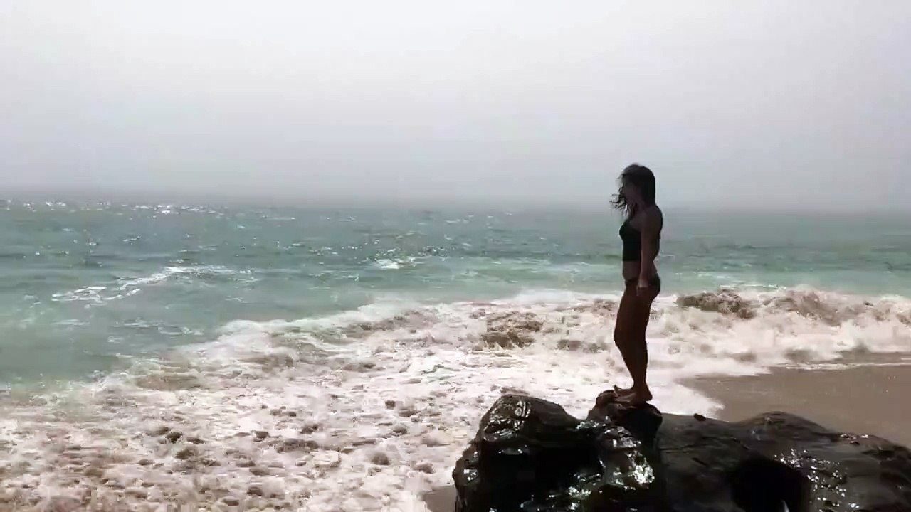 Une fille fait la belle au bord de la mer et finit par se prendre une vague !
