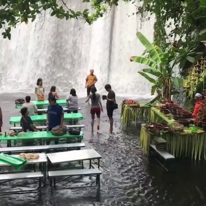 Un restaurant les pieds dans l'eau en face d'une chute d'eau magnifique